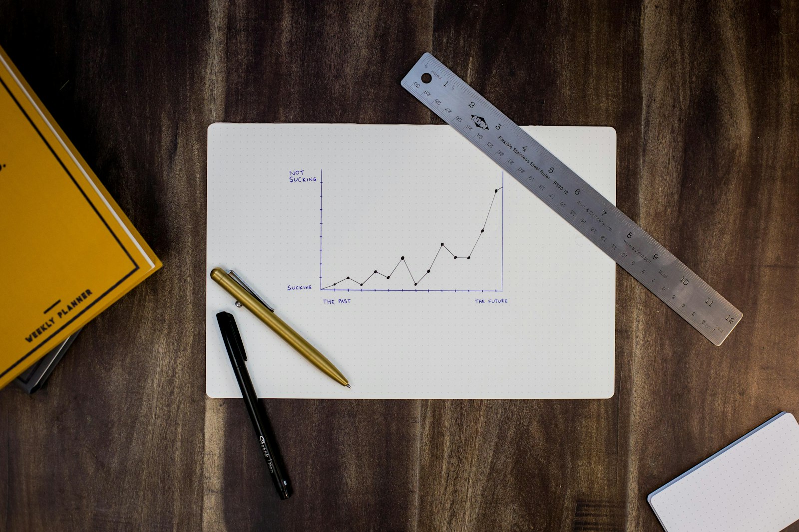 Hand sketching a growth chart on paper next to a laptop